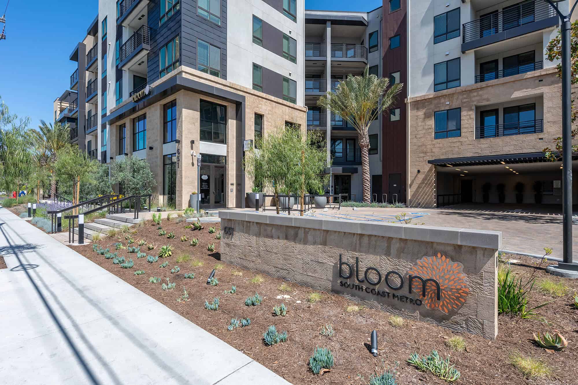 An exterior view of the apartment complex t with a visible sign for Bloom South Coast.