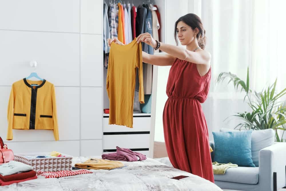 A woman organizing her bedroom and decluttering her wardrobe
