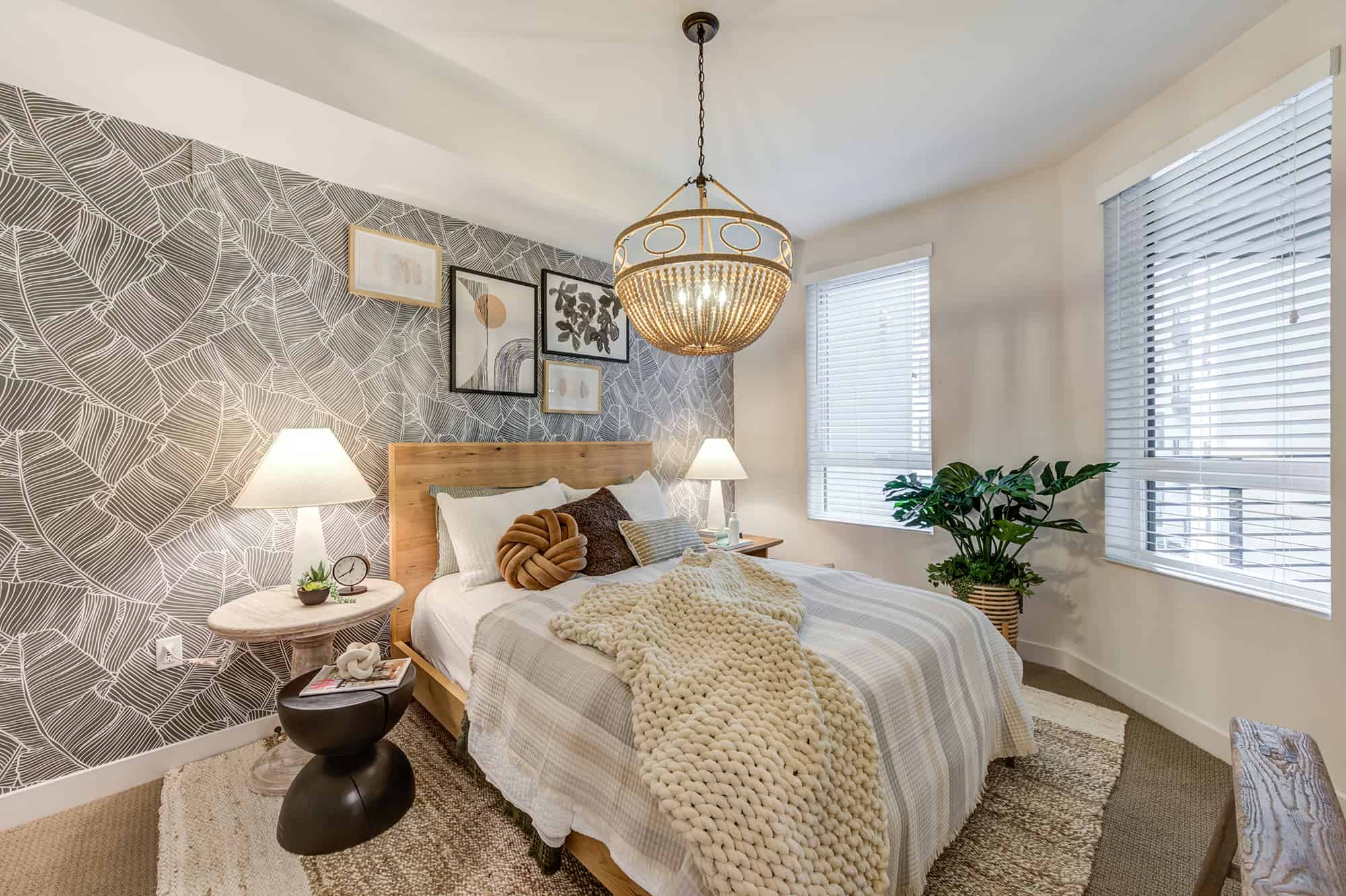A cozy bedroom with modern decor, including a woven pendant light, patterned wall, and comfortable bedding.